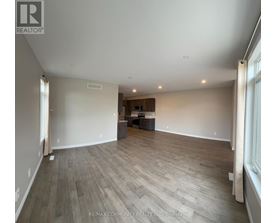 A spacious room with wooden flooring and a large window on the right side.