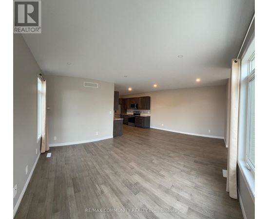 A spacious room with wooden flooring and a large window on the right side.