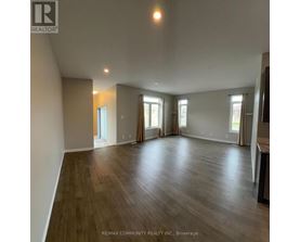 A spacious room with wood flooring and large windows.