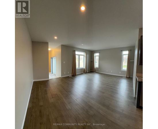 A spacious room with wood flooring and large windows.
