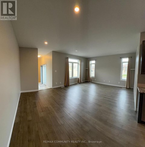 A spacious room with wood flooring and large windows.