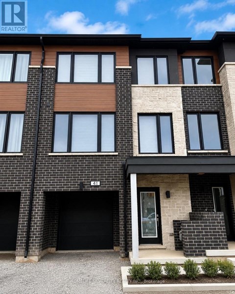 A modern two-story residential building with a black garage door.