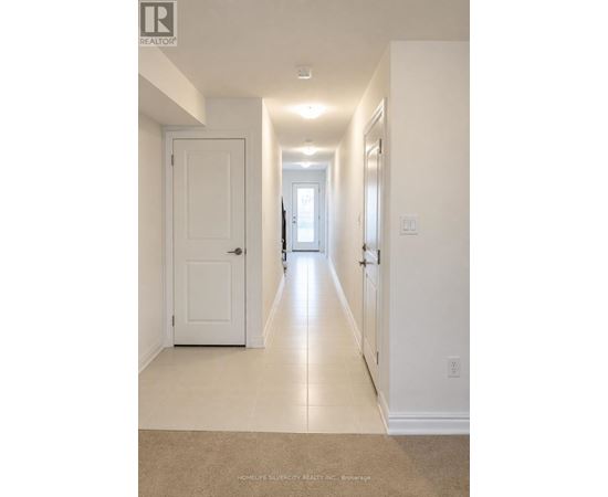 A long hallway with white walls and a carpeted floor.