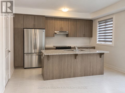 A kitchen with a refrigerator, sink, and cabinets.