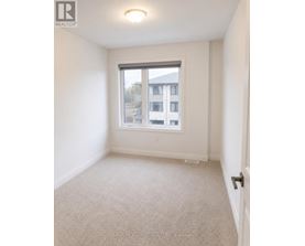 A white bedroom with a window and carpeted floor.