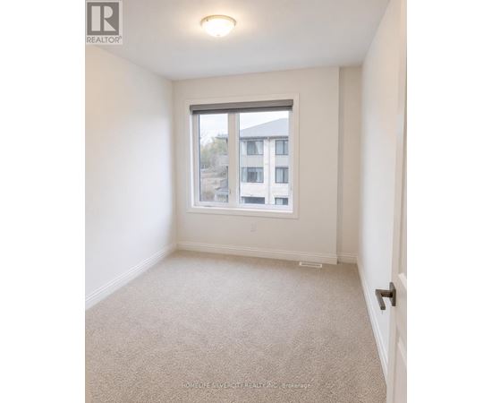 A white bedroom with a window and carpeted floor.
