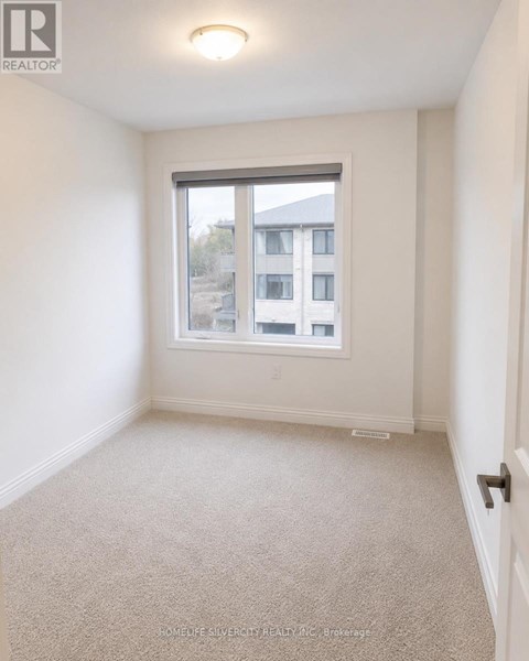 A white bedroom with a window and carpeted floor.