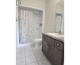 A white toilet with a gold shower curtain in a bathroom.