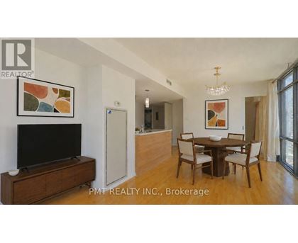 A living room with a TV, a dining table and chairs, and a painting on the wall.