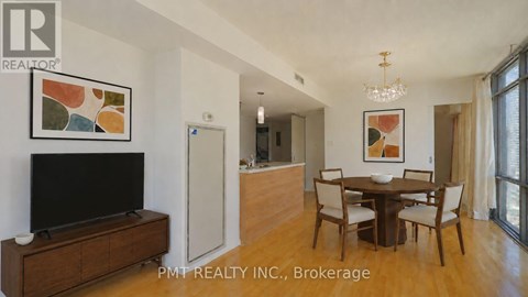 A living room with a TV, a dining table and chairs, and a painting on the wall.