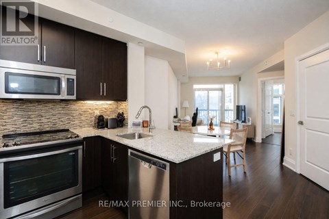 A kitchen with a stove top oven and microwave, a sink and a dining table with chairs.