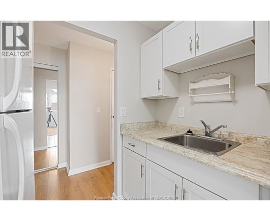 A kitchen with white cabinets and a marble countertop.