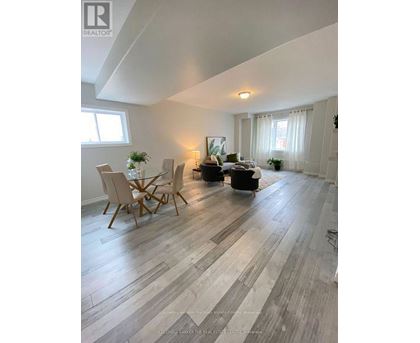 A living room with a wooden floor and a dining table with chairs.