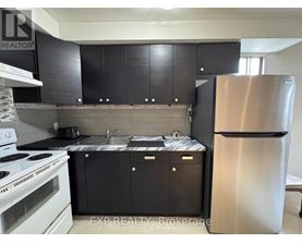 A kitchen with black cabinets and a stainless steel refrigerator.