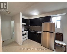 A kitchen with black cabinets and a stainless steel refrigerator.