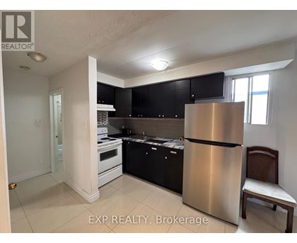 A kitchen with black cabinets and a stainless steel refrigerator.