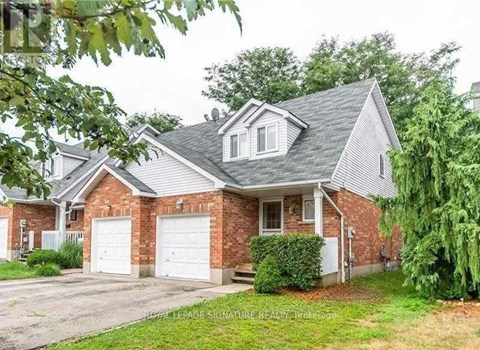 A house with a brick facade and a grey roof is surrounded by greenery.