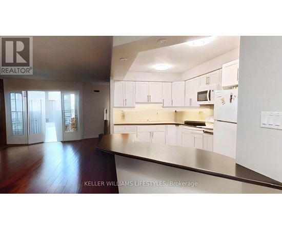 A modern kitchen with white cabinets and a wooden floor.