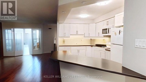 A modern kitchen with white cabinets and a wooden floor.