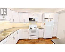 A kitchen with white appliances and cabinets.