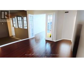 A room with a wooden floor and a doorway leading to another room.