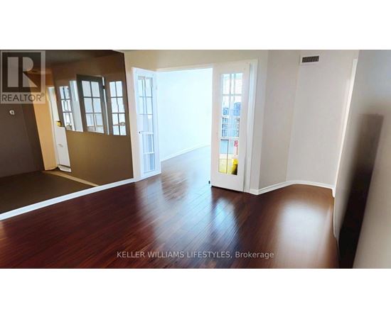 A room with a wooden floor and a doorway leading to another room.