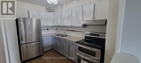 A kitchen with white cabinets and a stainless steel refrigerator.