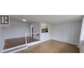 A spacious room with wooden flooring and white walls, featuring a balcony with a railing.