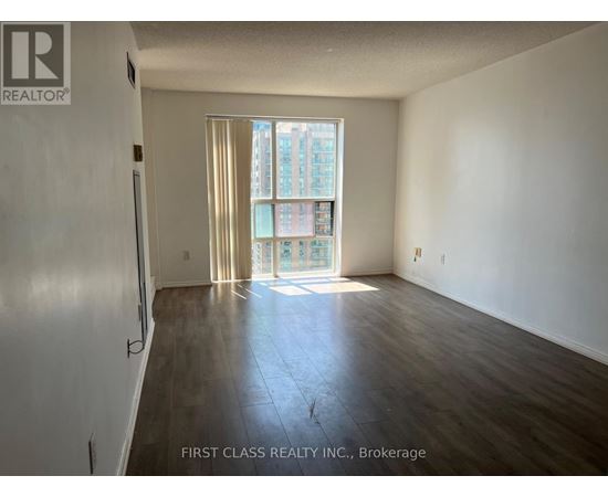 A room with wooden flooring and a large window with curtains.