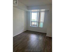 A room with wooden flooring and a window with a view of a building outside.
