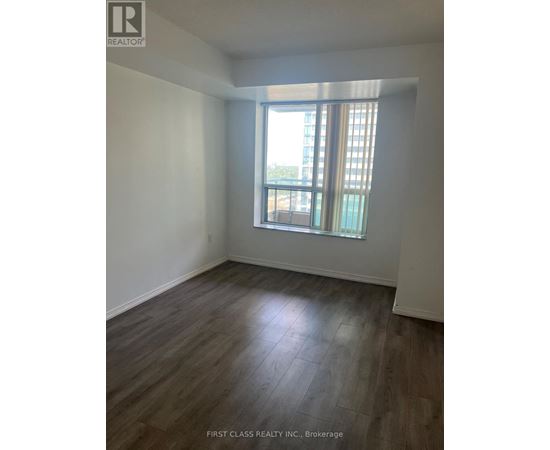 A room with wooden flooring and a window with a view of a building outside.