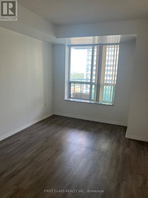 A room with wooden flooring and a window with a view of a building outside.