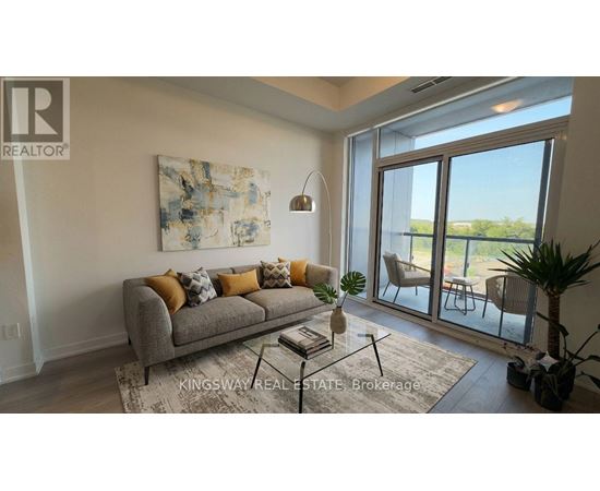 A living room with a grey couch and a painting on the wall.