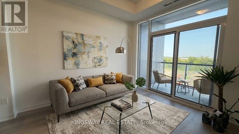 A living room with a grey couch and a painting on the wall.