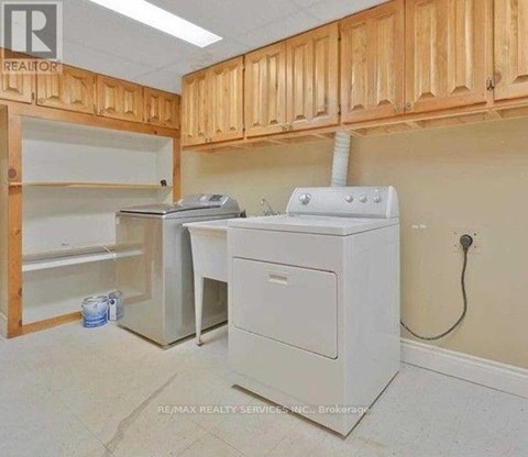 A white printer is on a desk in a room with wooden cabinets.
