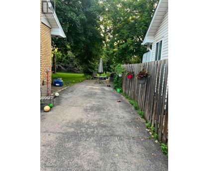 A residential alley with a wooden fence on one side and a house on the other.