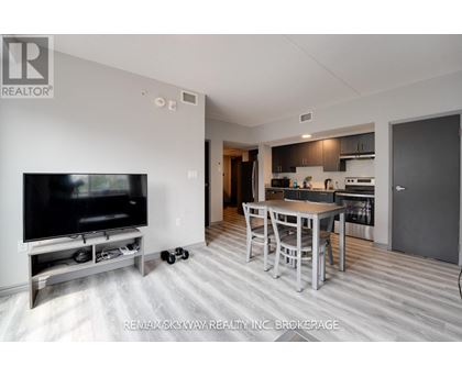 A modern living room with a television and a kitchen area in the background.
