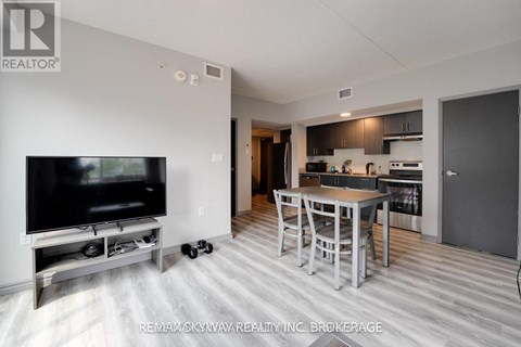 A modern living room with a television and a kitchen area in the background.