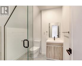 A bathroom with a toilet, sink and mirror.