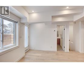 A spacious room with white walls and a large window.