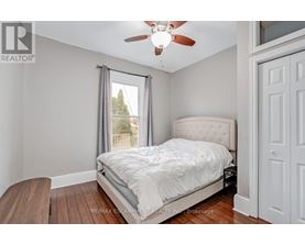 A bedroom with a bed, a ceiling fan, and a window with a view of trees.