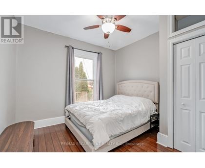 A bedroom with a bed, a ceiling fan, and a window with a view of trees.