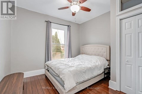 A bedroom with a bed, a ceiling fan, and a window with a view of trees.