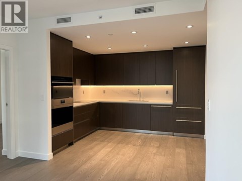 A modern kitchen with dark brown cabinets and a wooden floor.
