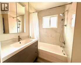 A white bathroom with a tub, sink, and mirror.
