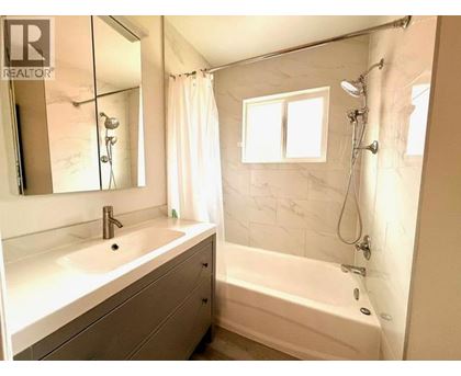 A white bathroom with a tub, sink, and mirror.