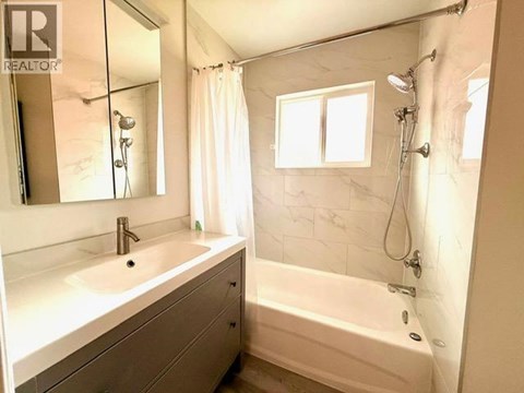 A white bathroom with a tub, sink, and mirror.