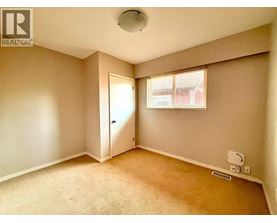 A room with a carpeted floor and a window with blinds.
