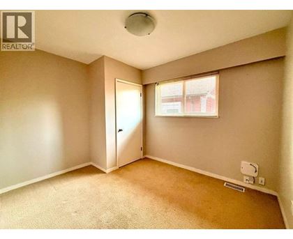A room with a carpeted floor and a window with blinds.