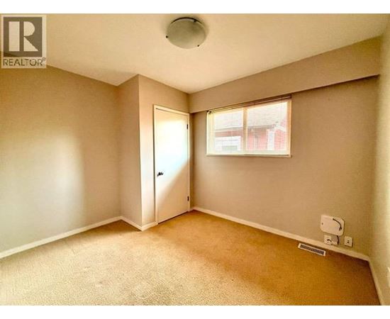 A room with a carpeted floor and a window with blinds.